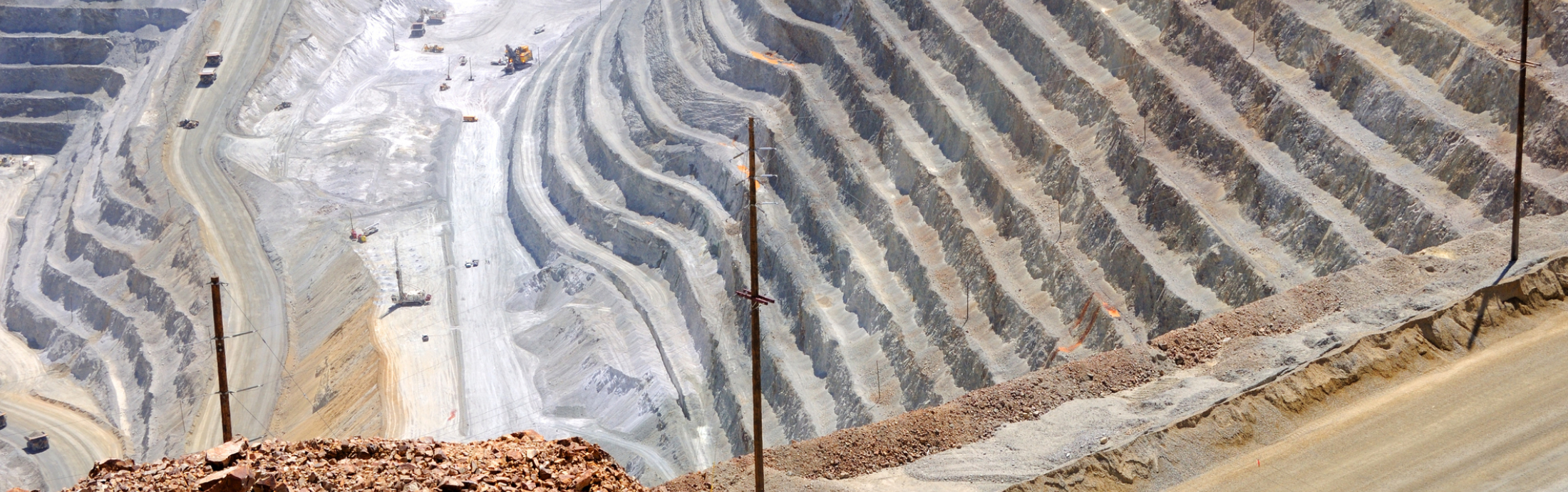 Aerial view of an open-pit copper mine. A vehicle travels along a winding dirt road.