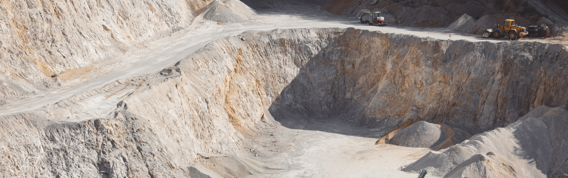 Heavy machinery in a quarry surrounded by piles of gravel.