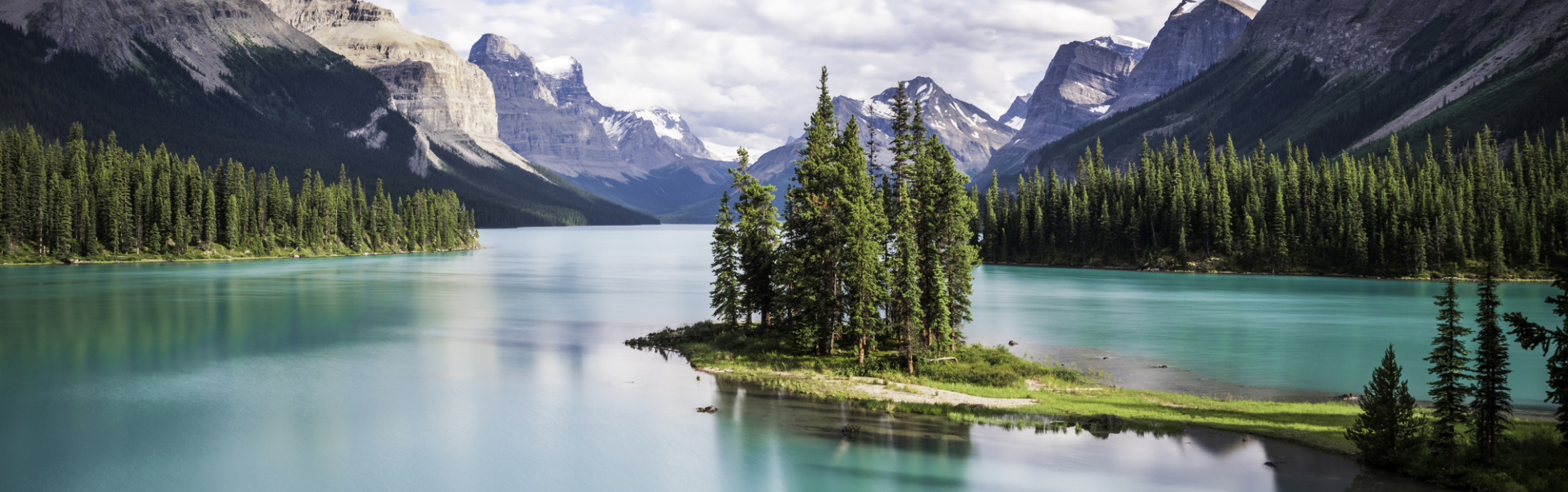 An island in the middle of a lake with mountains in the background.