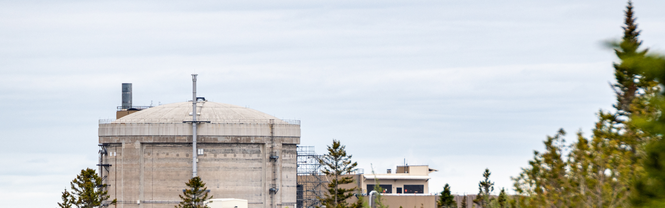 A distant view of a nuclear generating station through the woods.