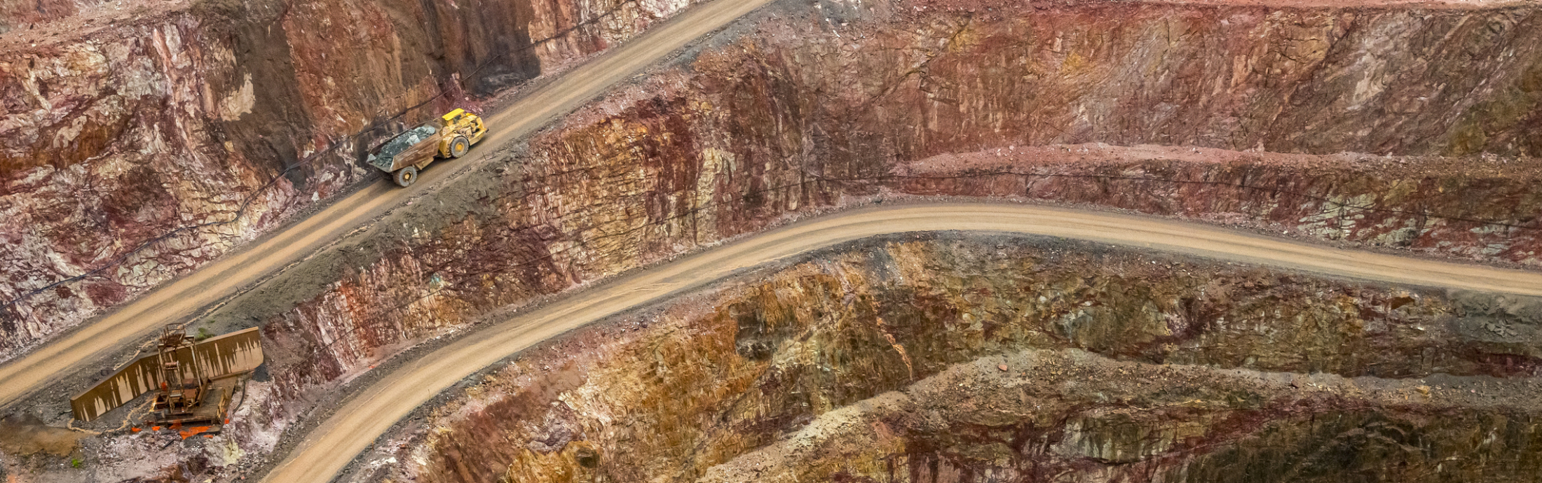 An open mine with haul truck driving up road.