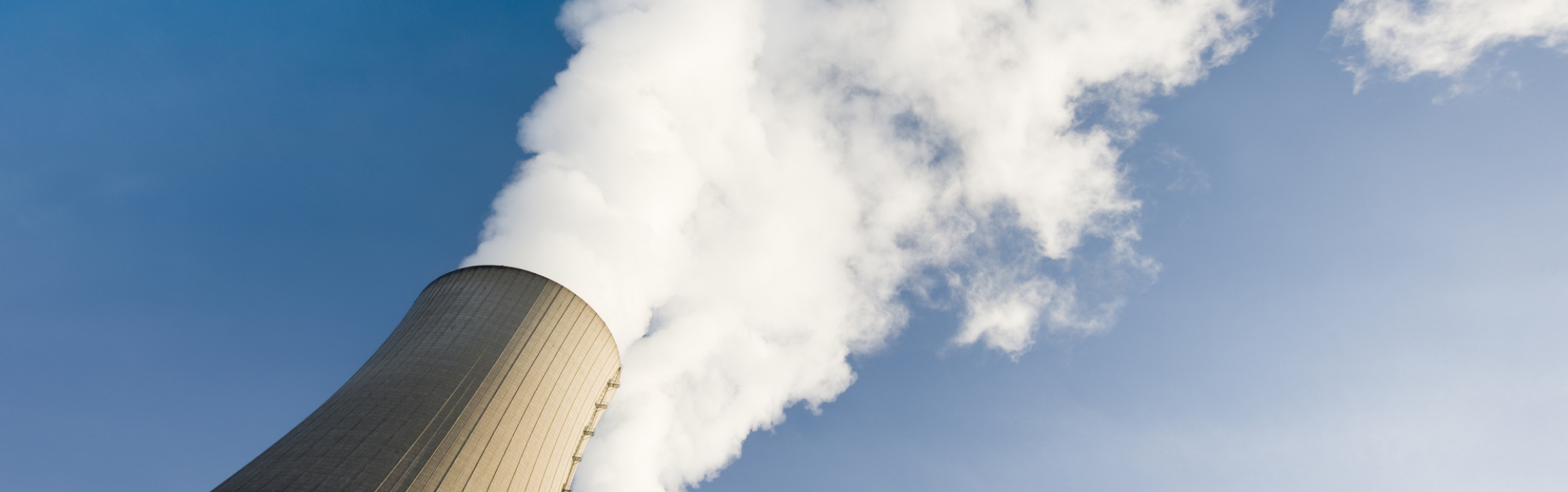 Two steaming cooling towers against blue sky.