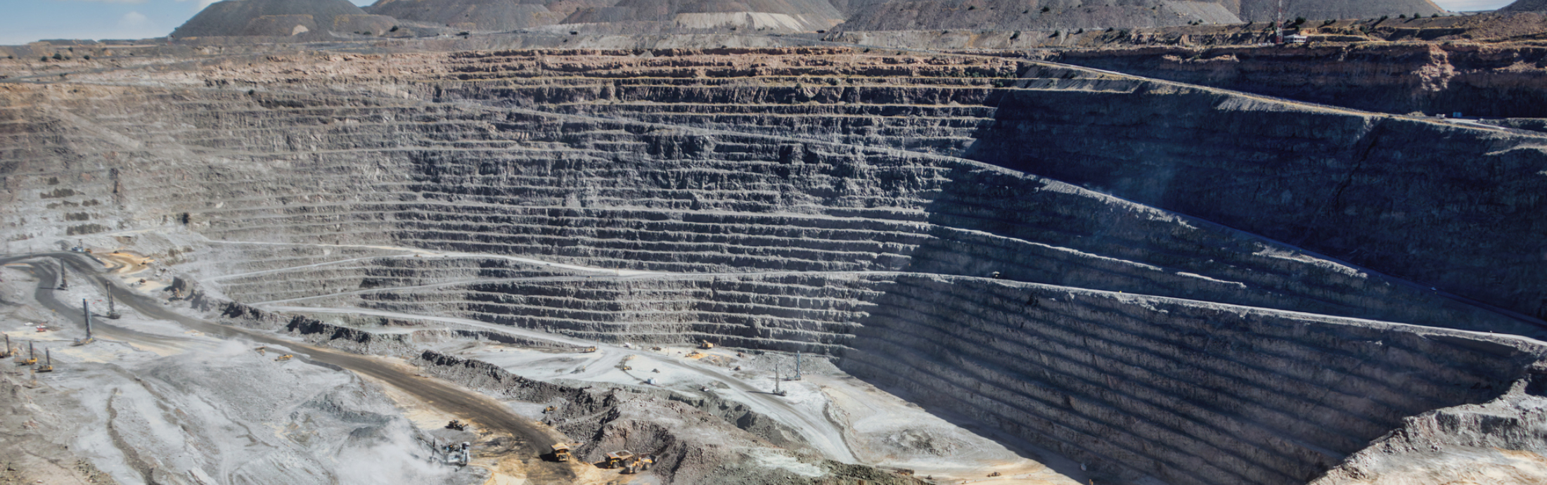 Panoramic view of an open pit mine with machinery in the background.