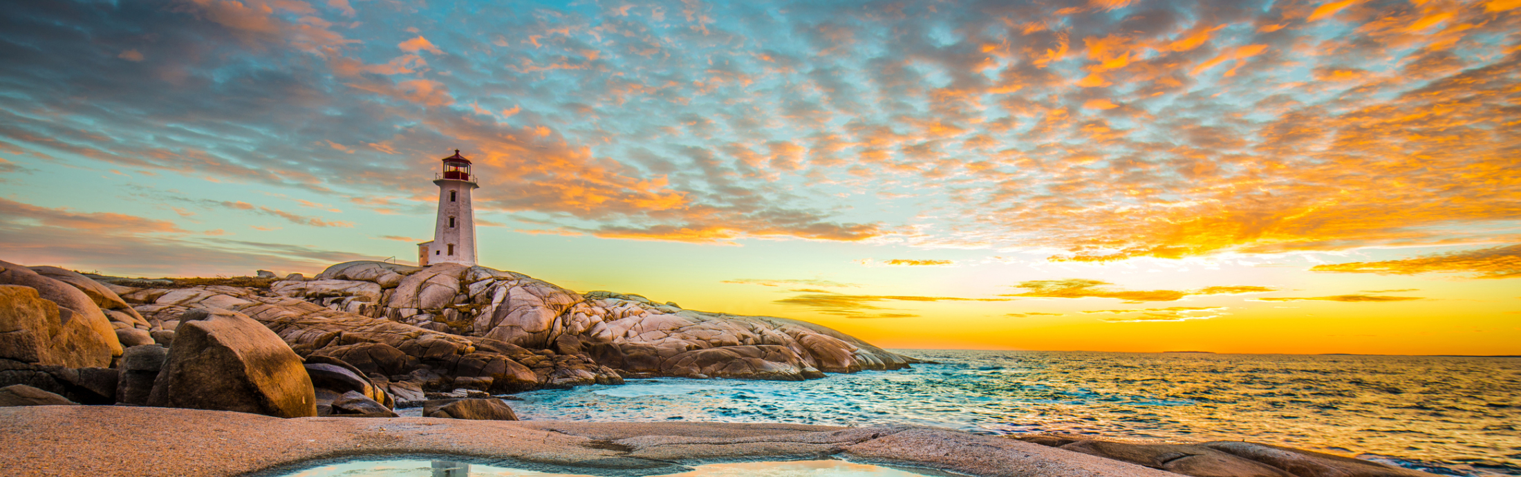 Panoramic view of the lake with a light house in a distance during sunset
