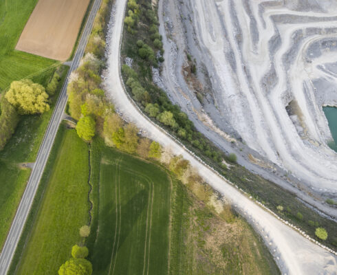 Aerial view of a large limestone quarry, fields, and a road.