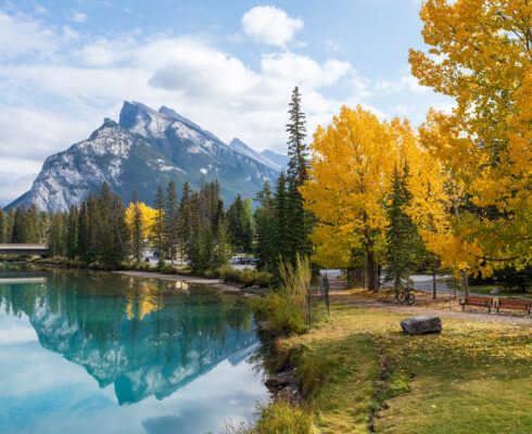 A serene lake surrounded by trees with mountains in the background.