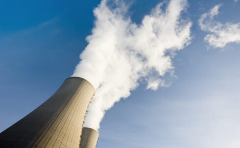 Two steaming cooling towers against blue sky.