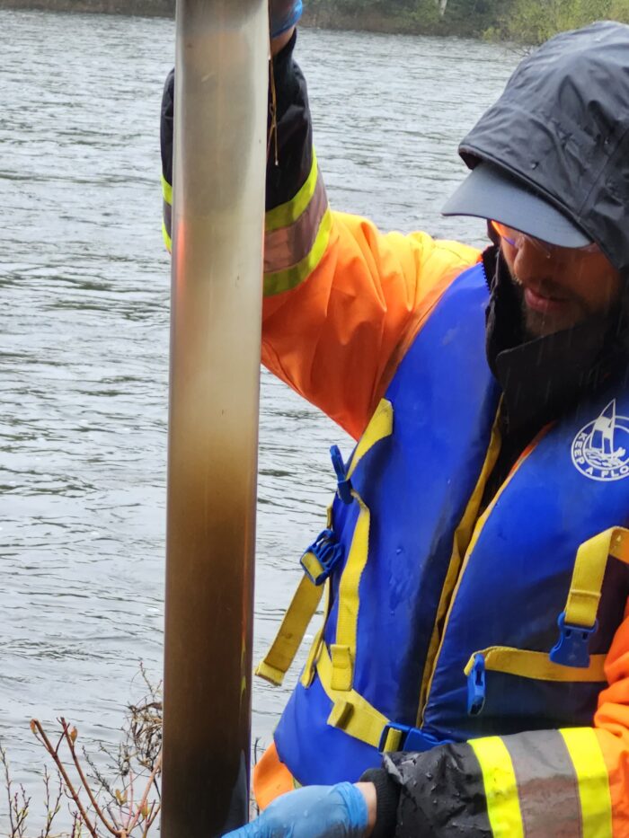 An Ecometrix expert wearing a life jacket core sampling with water in the background.