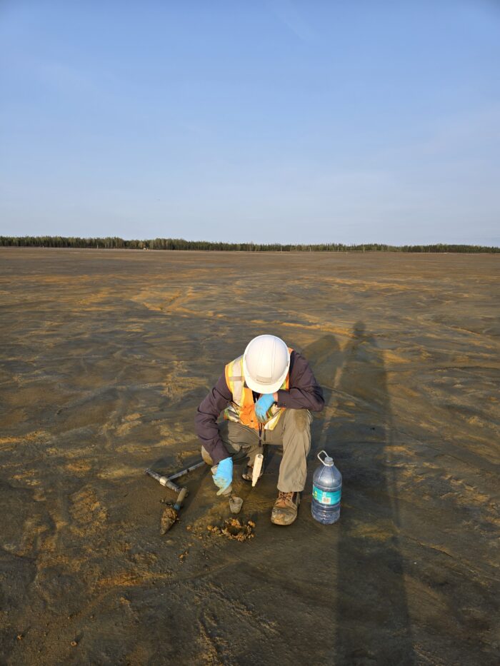 An Ecometrix expert wearing protective gear, collecting a tailings sample.