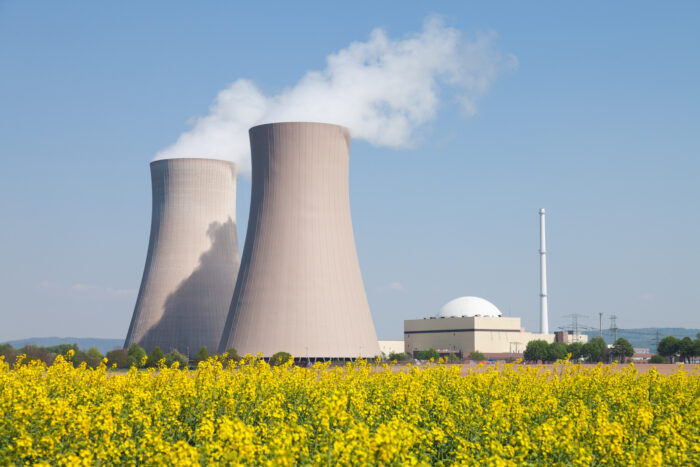 Nuclear power station with steaming cooling towers and canola field.