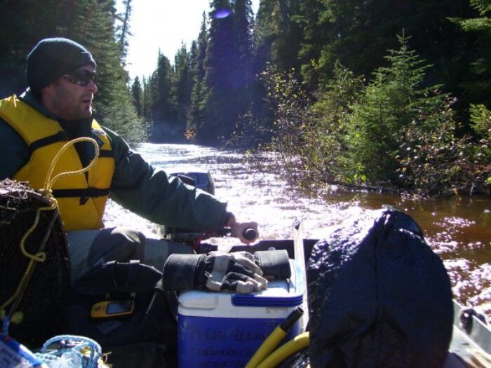 Jason Dietrich in the field, driving a boat.