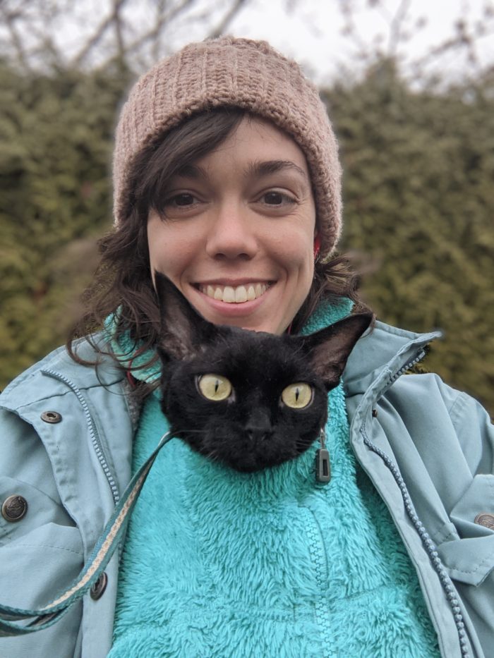 A portrait image of Mackenzie Bromstad with her cat’s head poking out of her jumper.