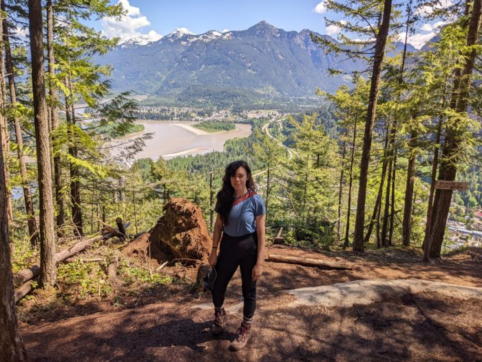 Mackenzie Bromstad standing in an elevated part of the forest with a mountain range behind her.